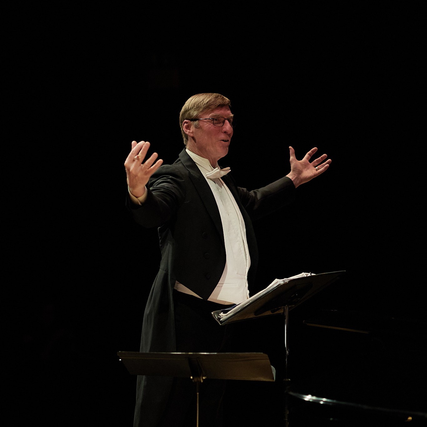 MGC3618-2 Photo of the conductor with his arms and hands spread out and smile on his face.